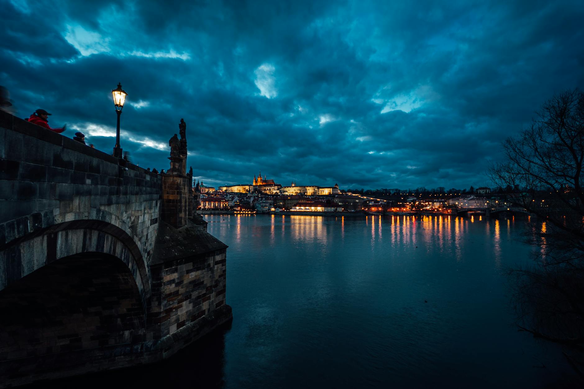 Puente de Carlos iluminado al atardecer reflejado en el Vltava en Praga