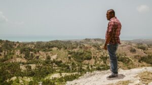 Hombre en un acantilado de Haití mirando al océano y al paisaje montañoso del interior