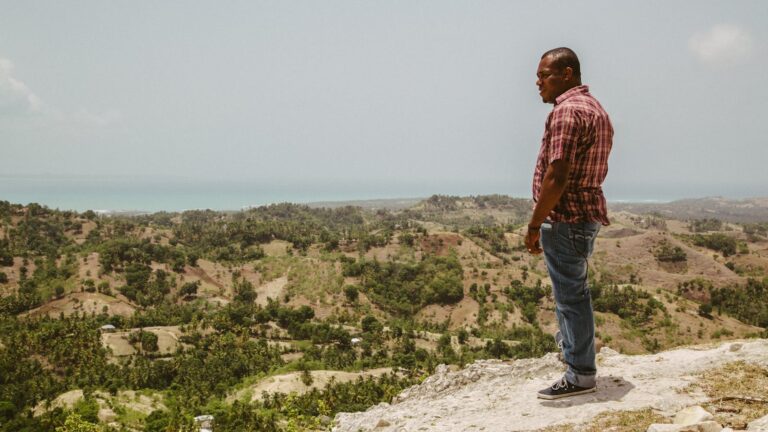 Hombre en un acantilado de Haití mirando al océano y al paisaje montañoso del interior
