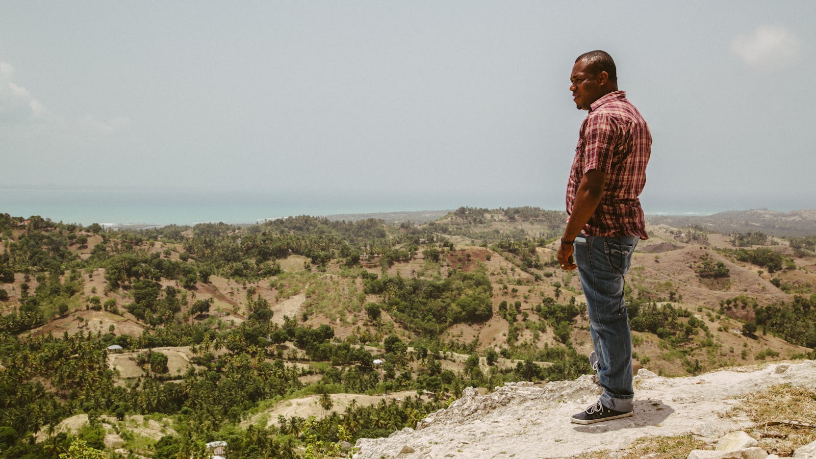 Puerto Príncipe en 2026: guía honesta de la capital de Haití (y por qué hoy no se viaja) 1 Hombre en un acantilado de Haití mirando al océano y al paisaje montañoso del interior