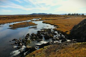 Rio islandes serpenteante entre vegetacion otonal y montanas al fondo, paisaje tipico de pesca de salmon