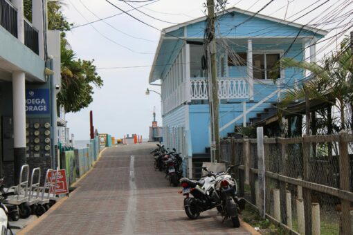 Calle de Utila con casa azul y motos aparcadas, isla de Honduras en el Caribe