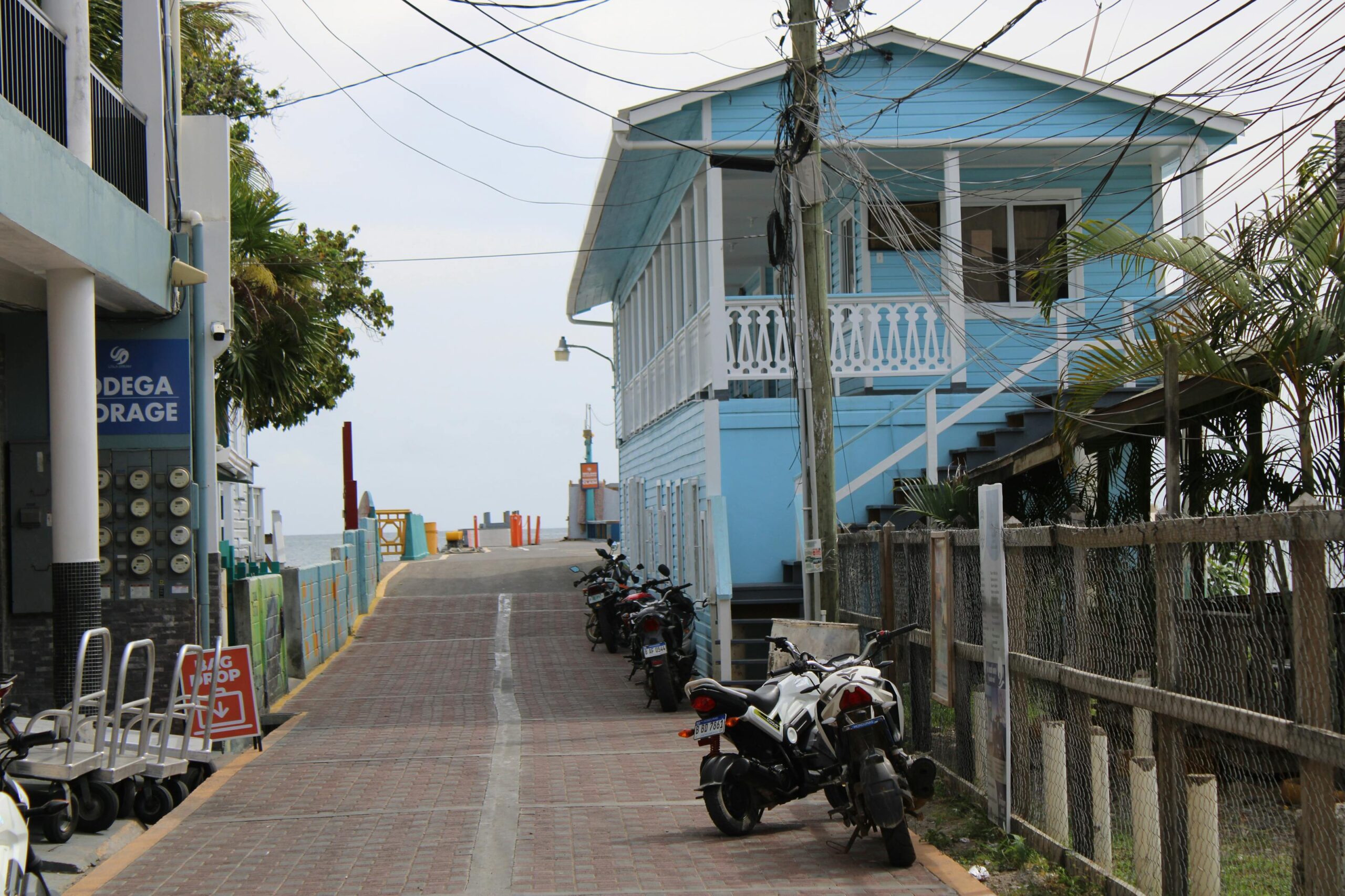 Calle de Utila con casa azul y motos aparcadas, isla de Honduras en el Caribe