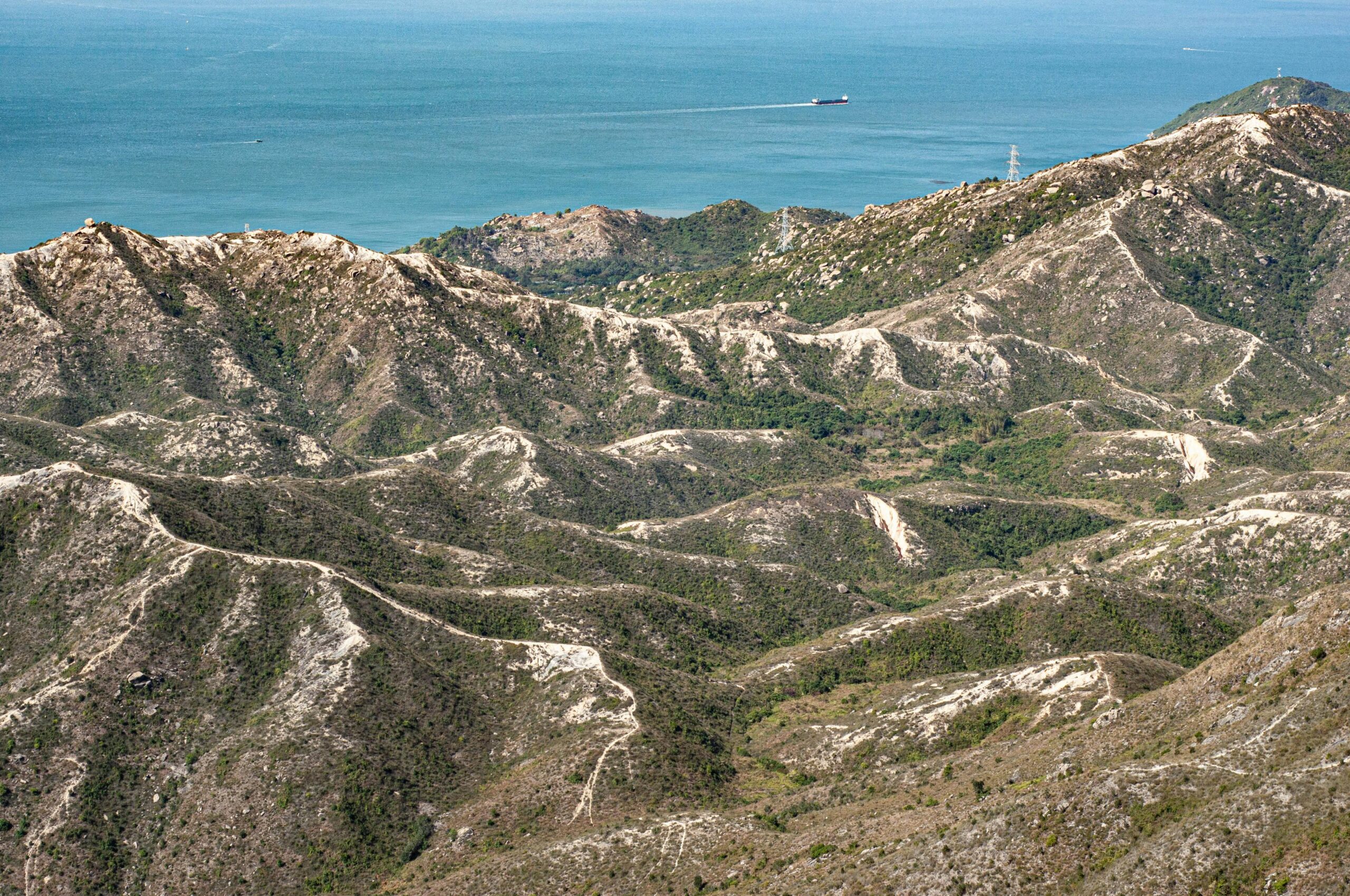 Hong Kong naturaleza: guía 2026 para descubrir parques, senderos y la cara verde que casi nadie cuenta 2 Vista aérea de las montañas escarpadas de Hong Kong llegando al mar