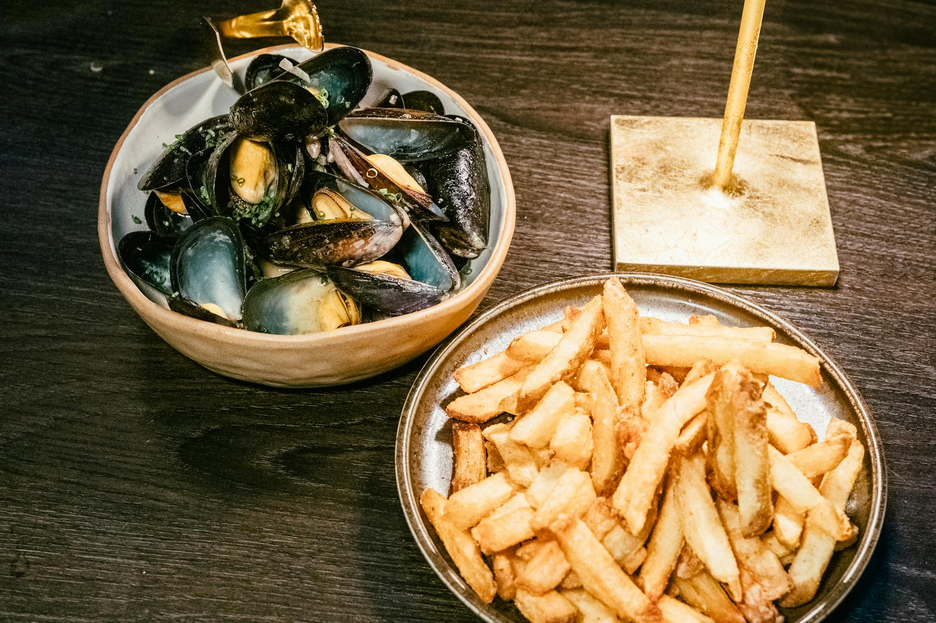 Plato de moules-frites belgas con mejillones al vapor y patatas fritas crujientes