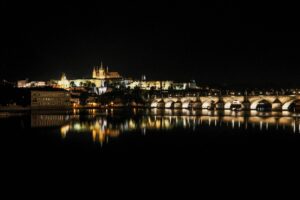 Castillo de Praga y Puente de Carlos iluminados de noche reflejados en el río Vltava