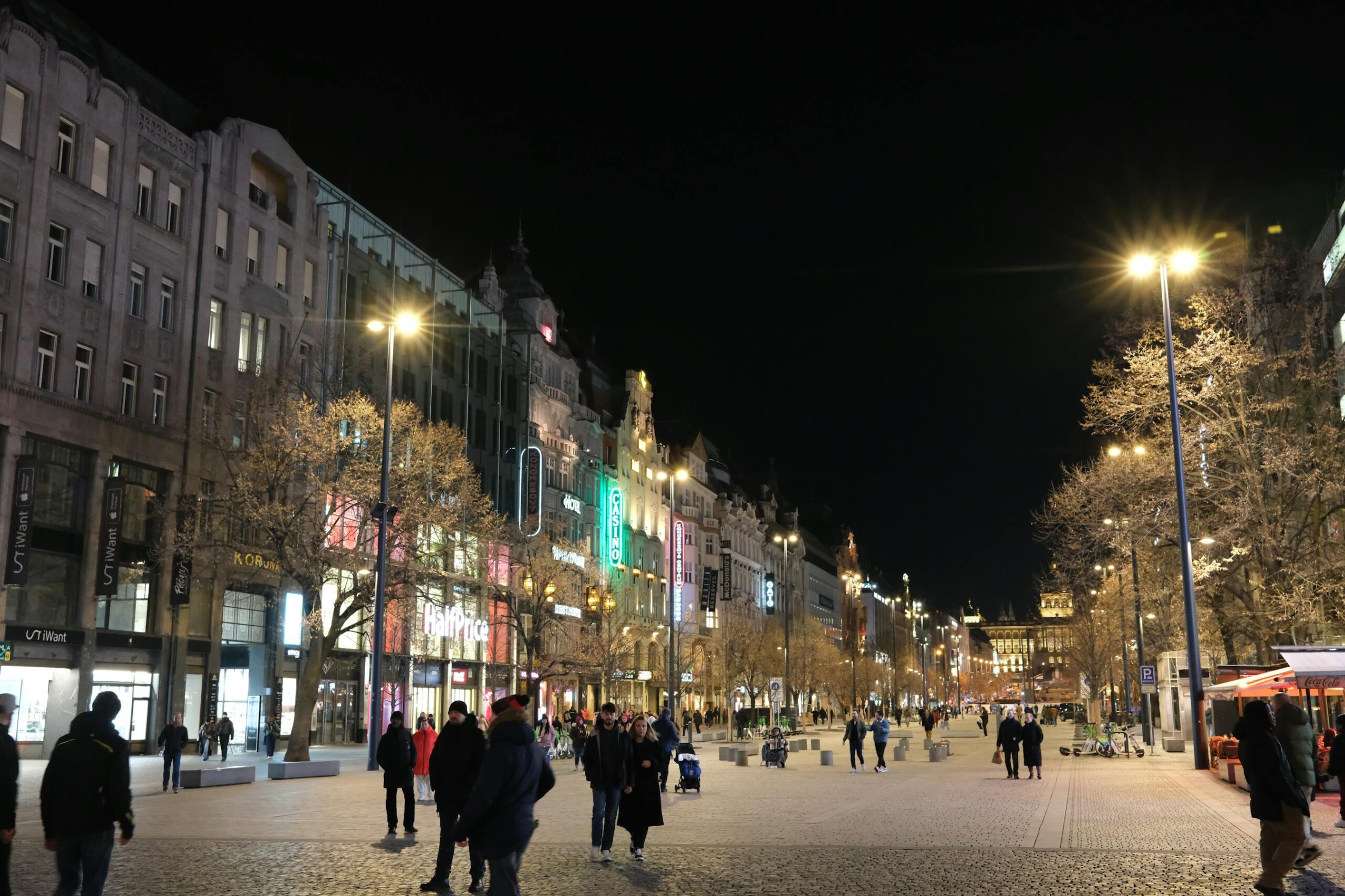 Calle del centro de Praga iluminada de noche con escaparates y comercios