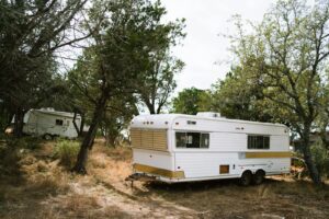 Mini-trailer de camping aparcado entre árboles en un bosque