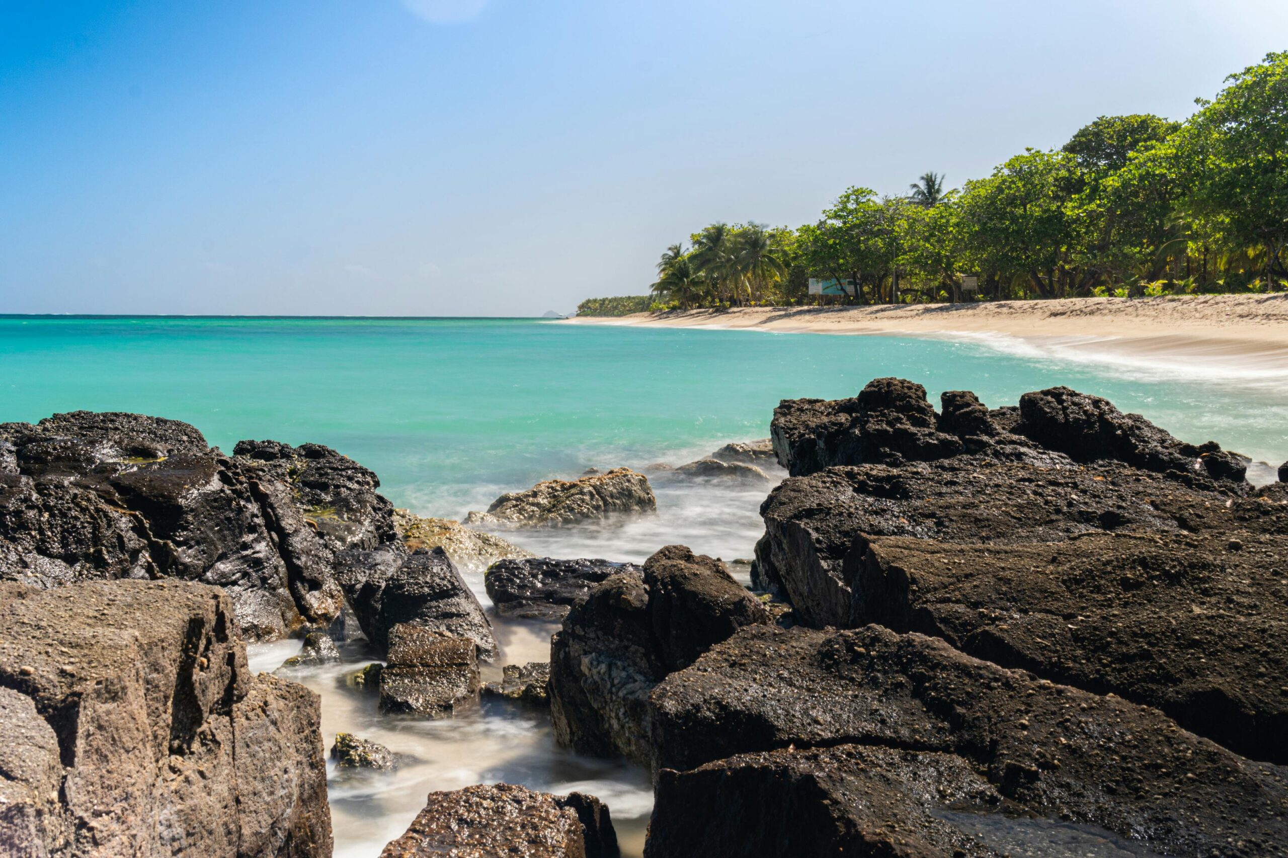 Playa caribeña de Honduras con agua turquesa y rocas volcánicas negras
