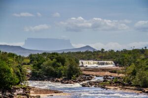 Cascada del Parque Nacional Canaima en Venezuela con un tepuy al fondo y vegetacion exuberante