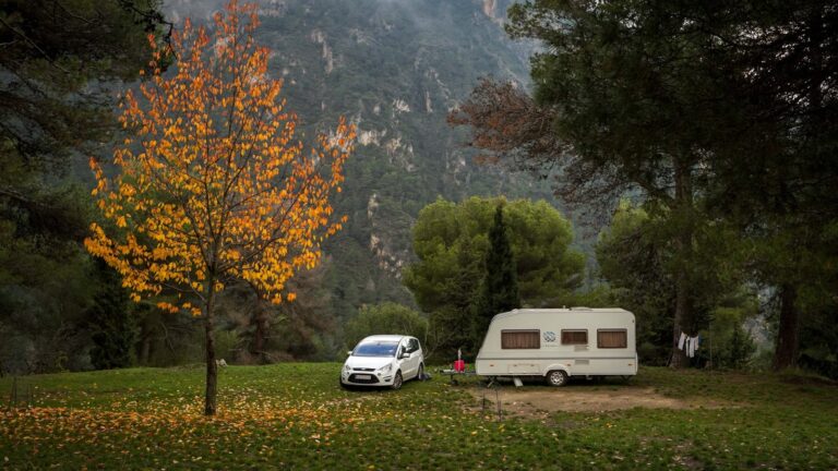 Coche con pequeño tráiler de camping en un paraje de Salobreña, España, con vegetación otoñal