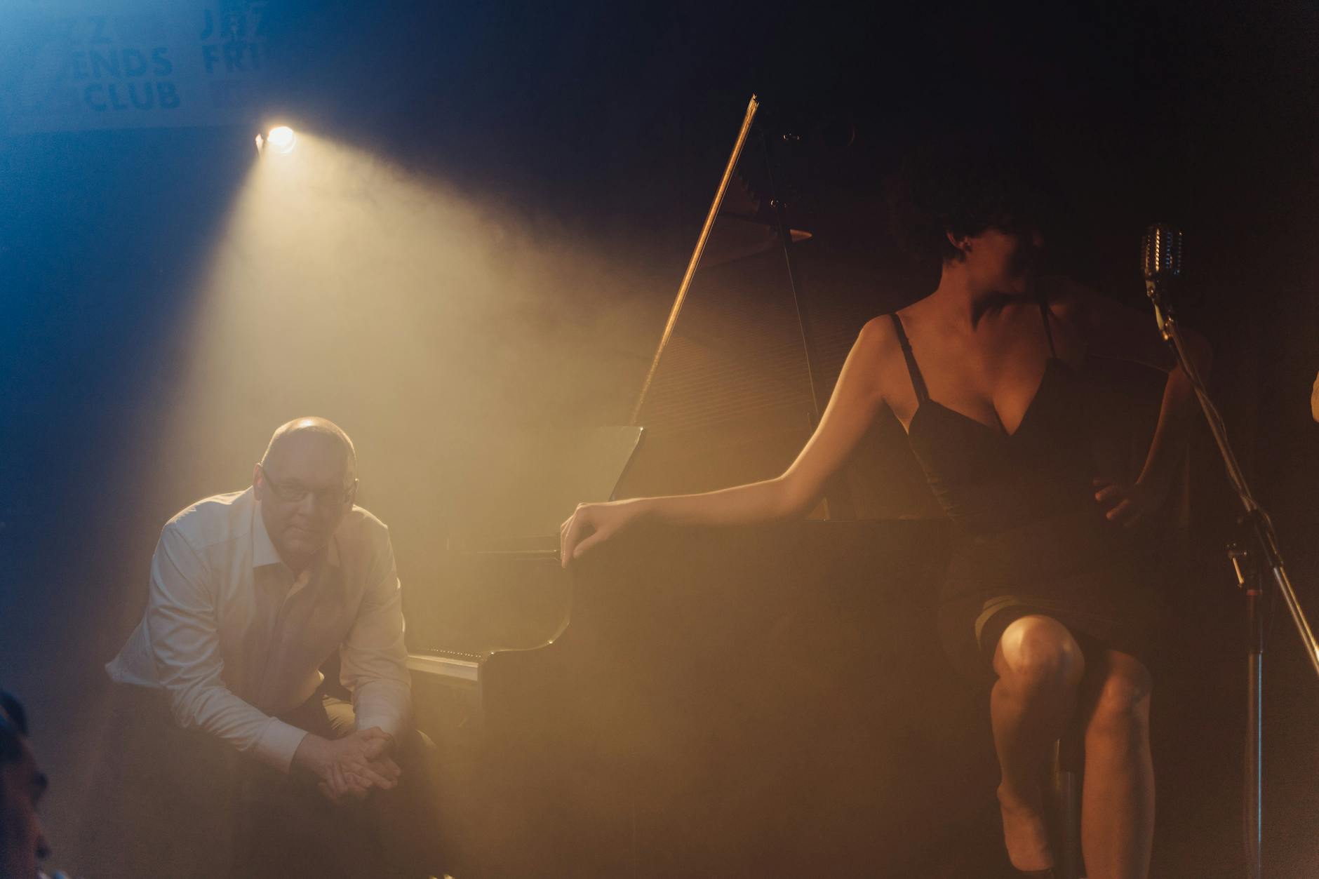 Pianista y cantante actuando en un club de jazz con luz tenue ambiente íntimo