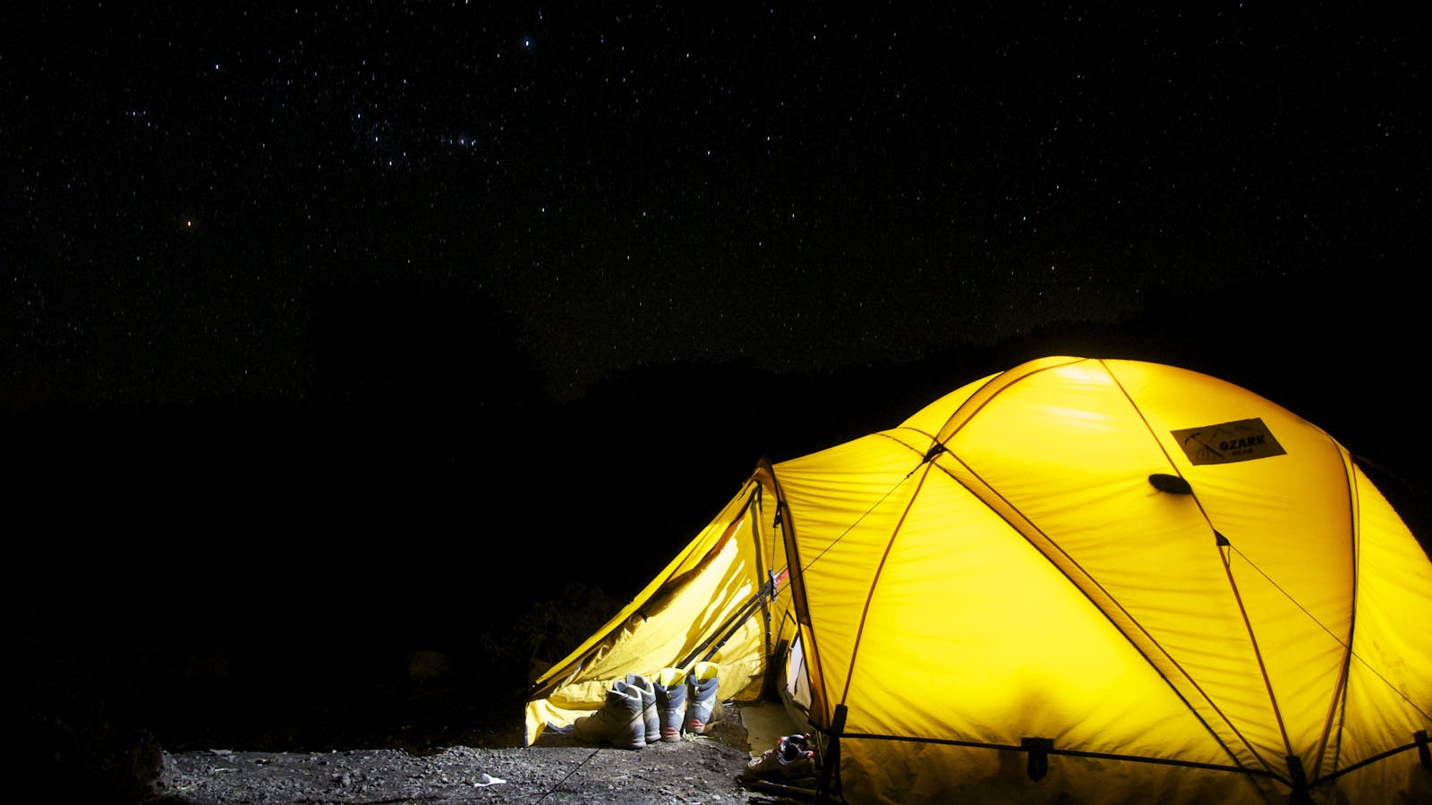 Tienda de camping iluminada bajo un cielo nocturno cuajado de estrellas