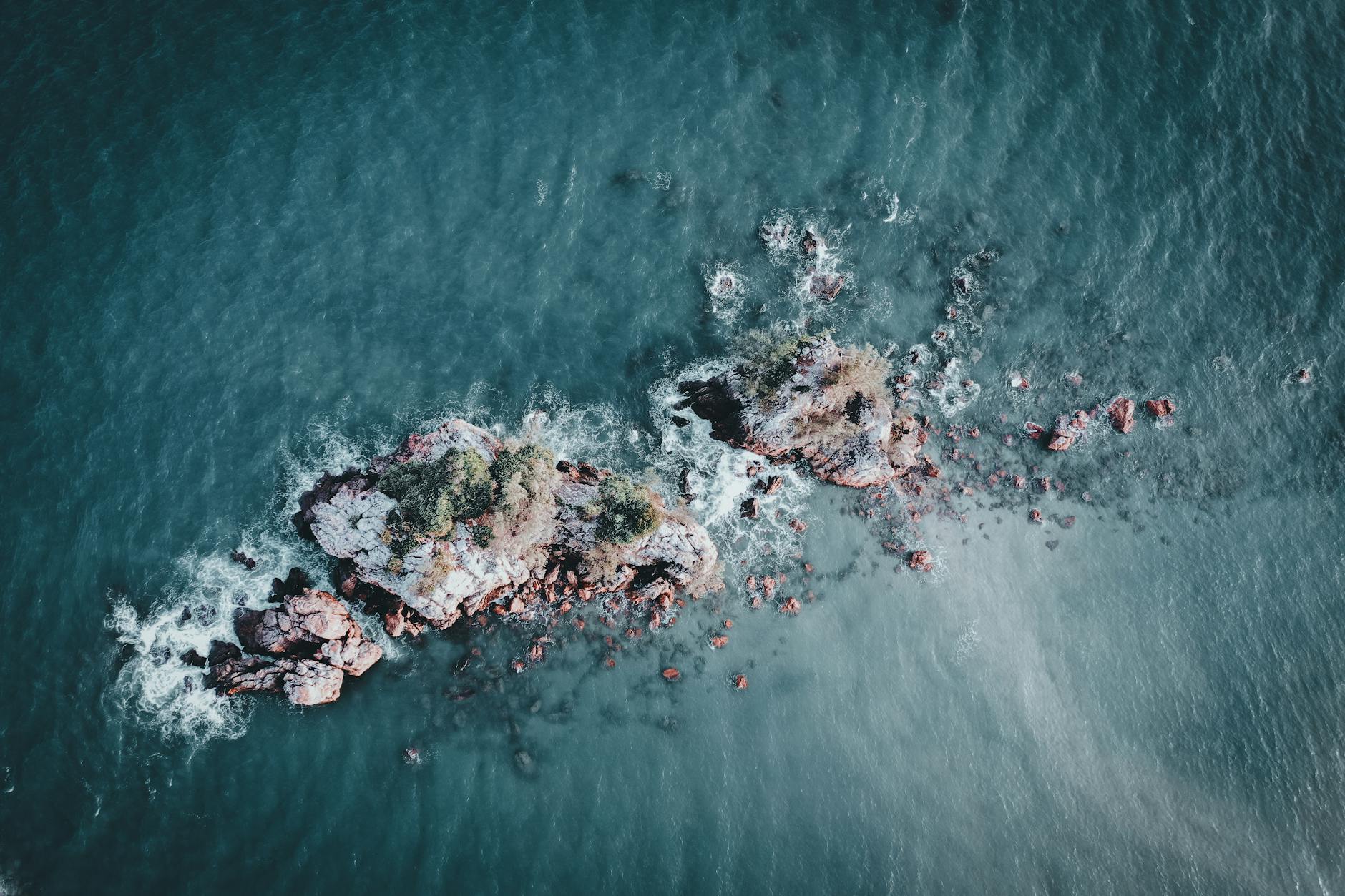 Isla pequeña con vegetación rodeada de aguas cristalinas vista desde el aire