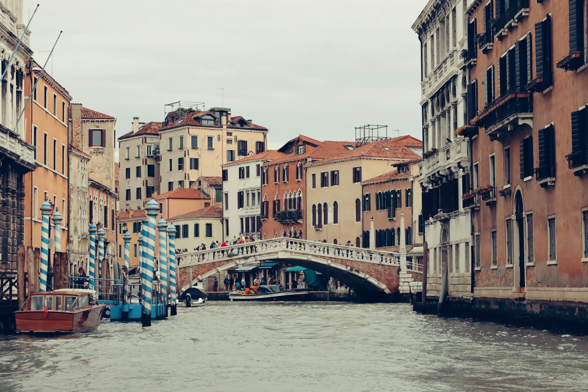 Puente sobre canal veneciano con arquitectura antigua al fondo y cielo despejado