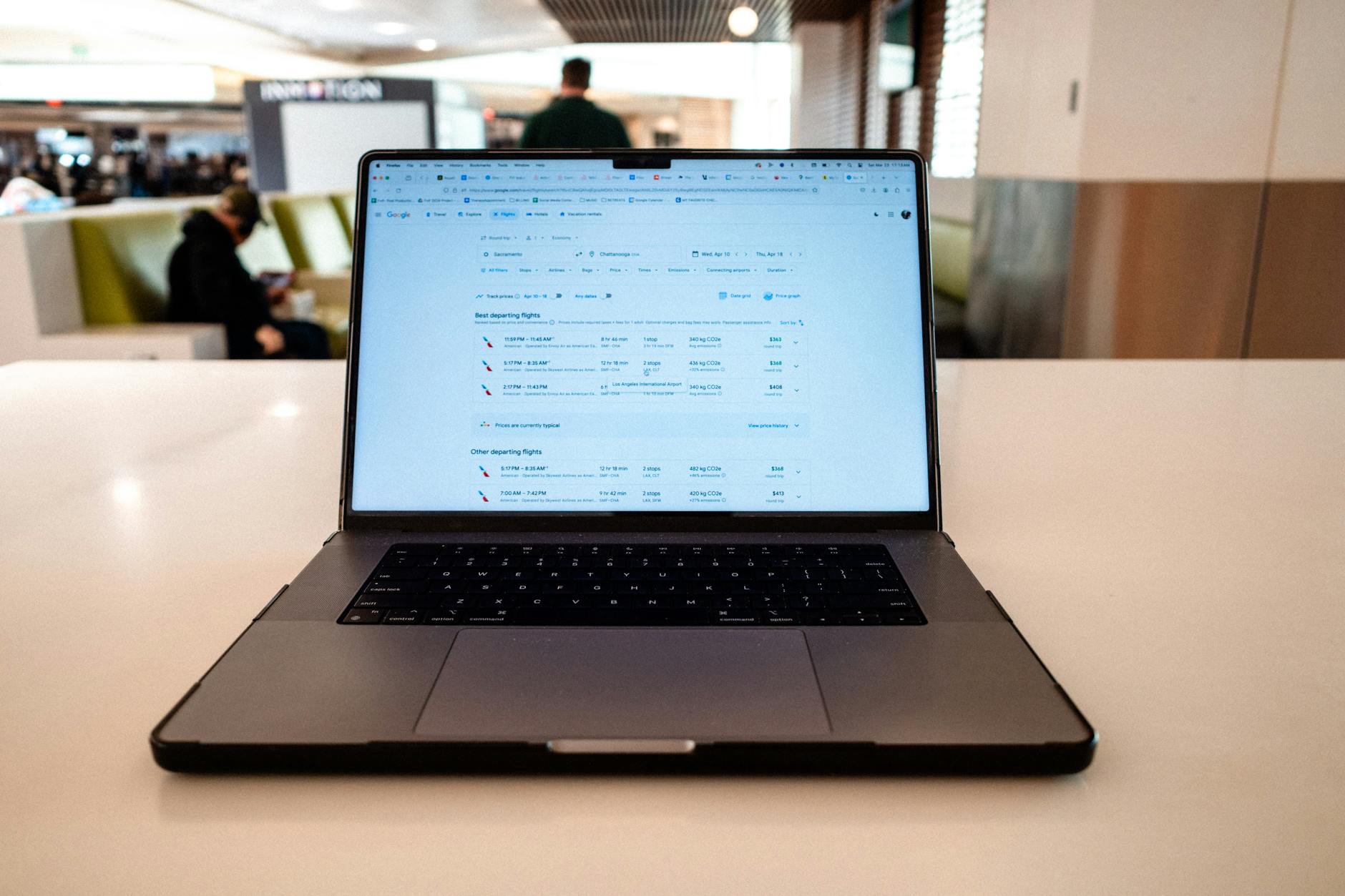 Cómo comprar viajes por internet: guía para 2026 1 Portátil con horarios de vuelo en sala de espera de aeropuerto