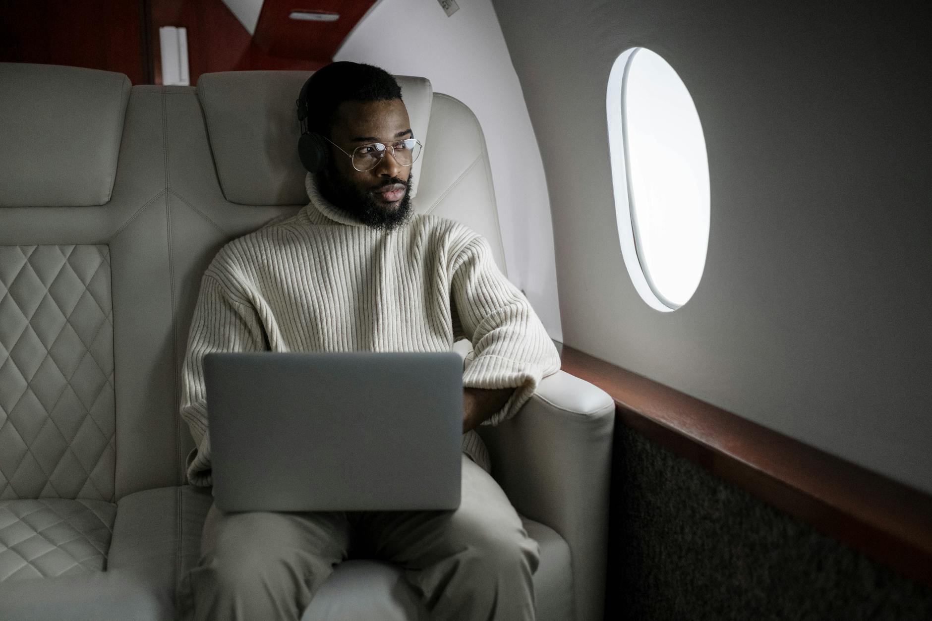 pasajero con auriculares usando portátil en cabina de avión