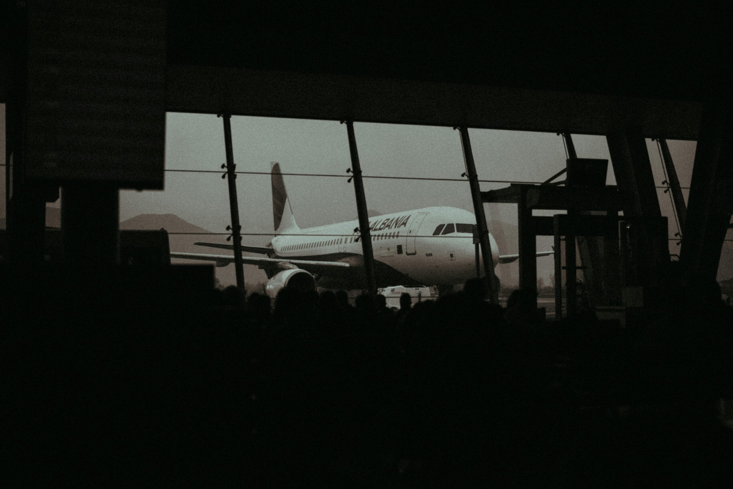 Pasajeros en sala de espera del aeropuerto ante silueta de avión