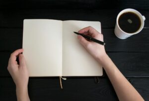 Viajera escribiendo en su cuaderno de crónicas de viaje en un café
