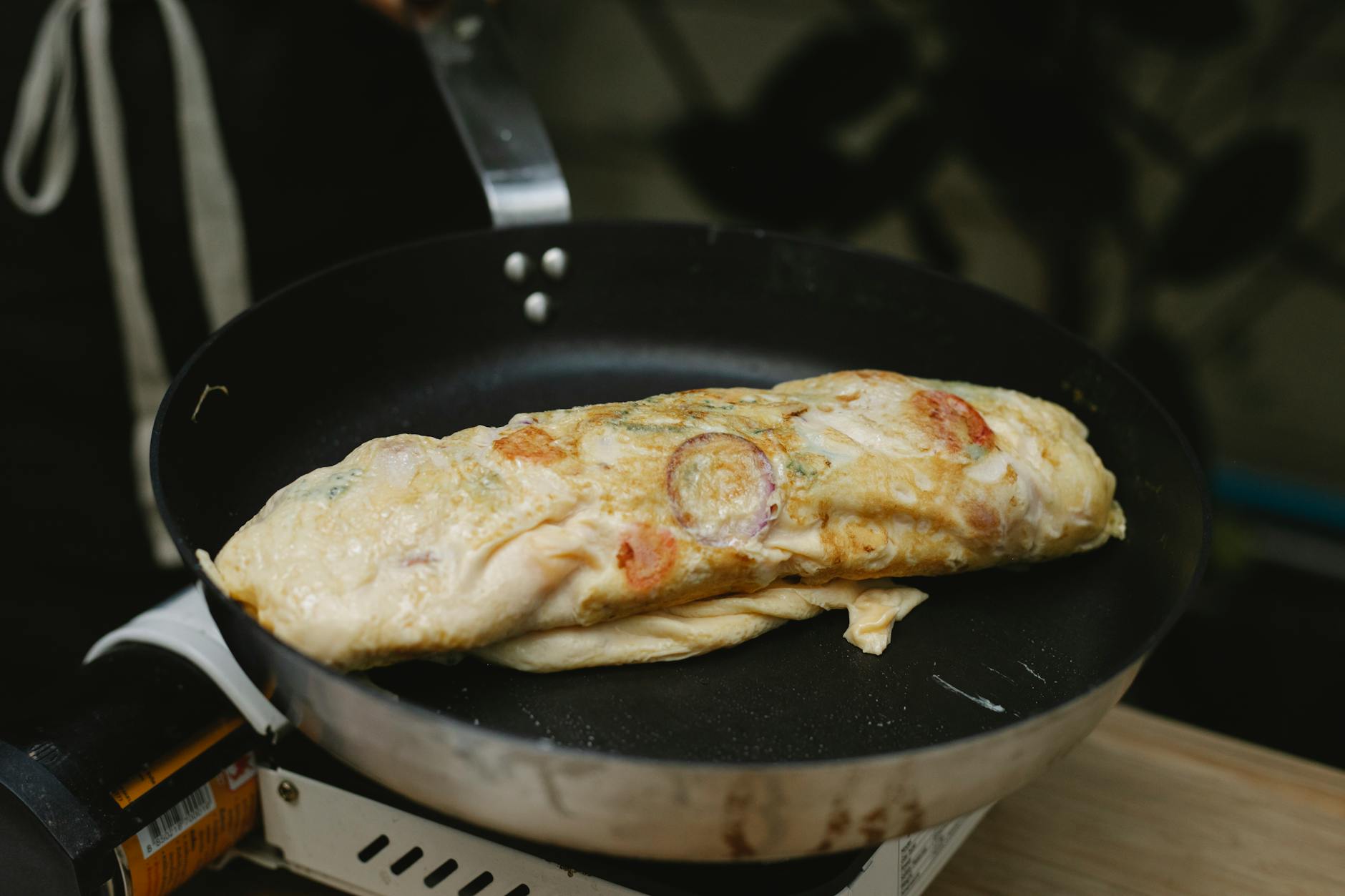 Tortilla francesa fresca en sartén cocinando con tomates y rábano