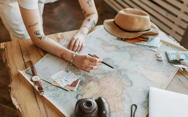 Mujer planificando un viaje con mapa del mundo, pasaportes y ordenador