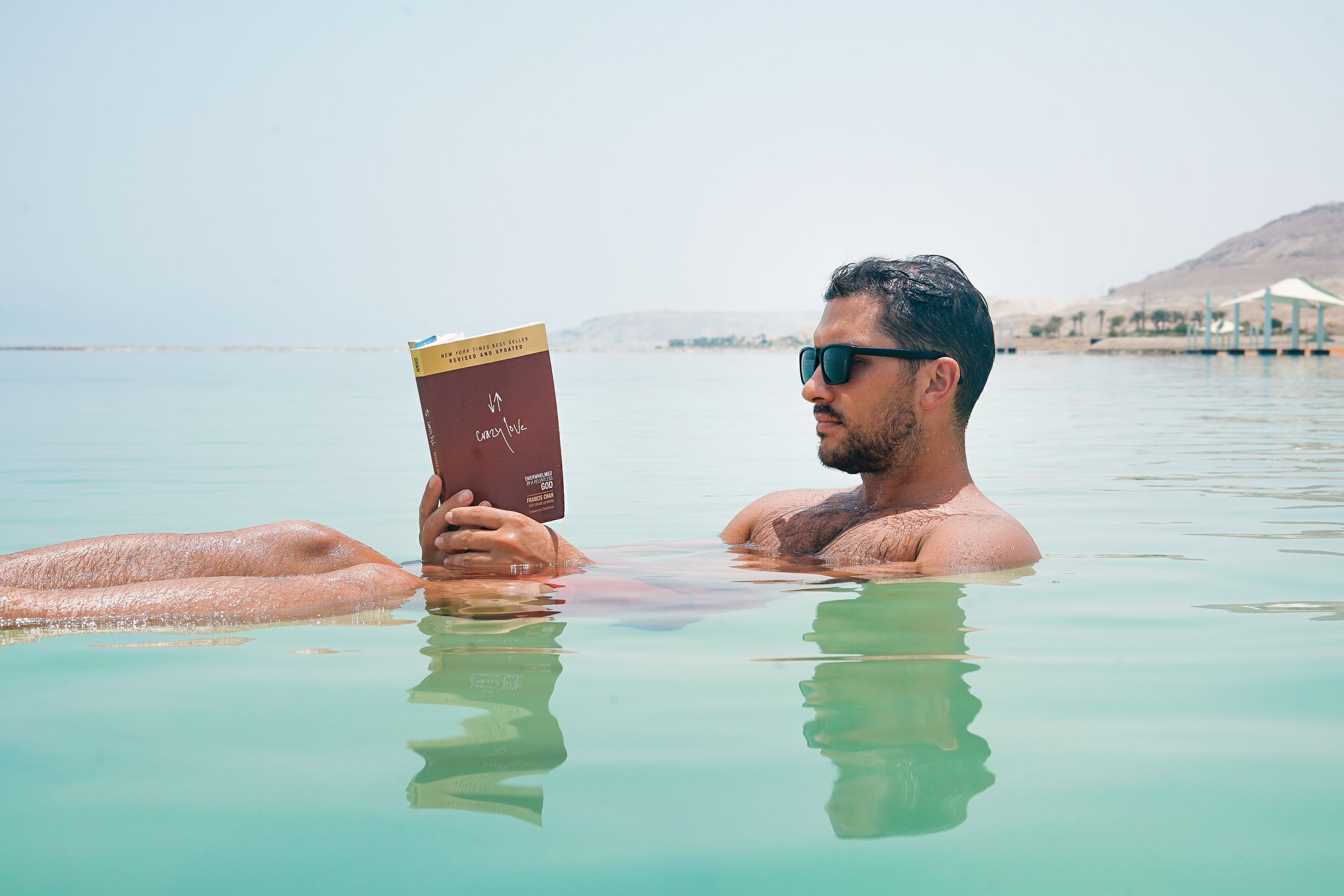 Israel en 2026: guía de Jerusalén, Tel Aviv y el Mar Muerto 2 Hombre flotando en el Mar Muerto leyendo un libro