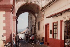 Calle empedrada de Taxco con casas blancas y la Catédral de Santa Prisca al fondo