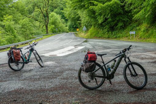 Ciclista de cicloturismo pedaleando por una carretera rural entre montañas
