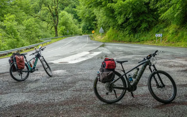 Ciclista de cicloturismo pedaleando por una carretera rural entre montañas