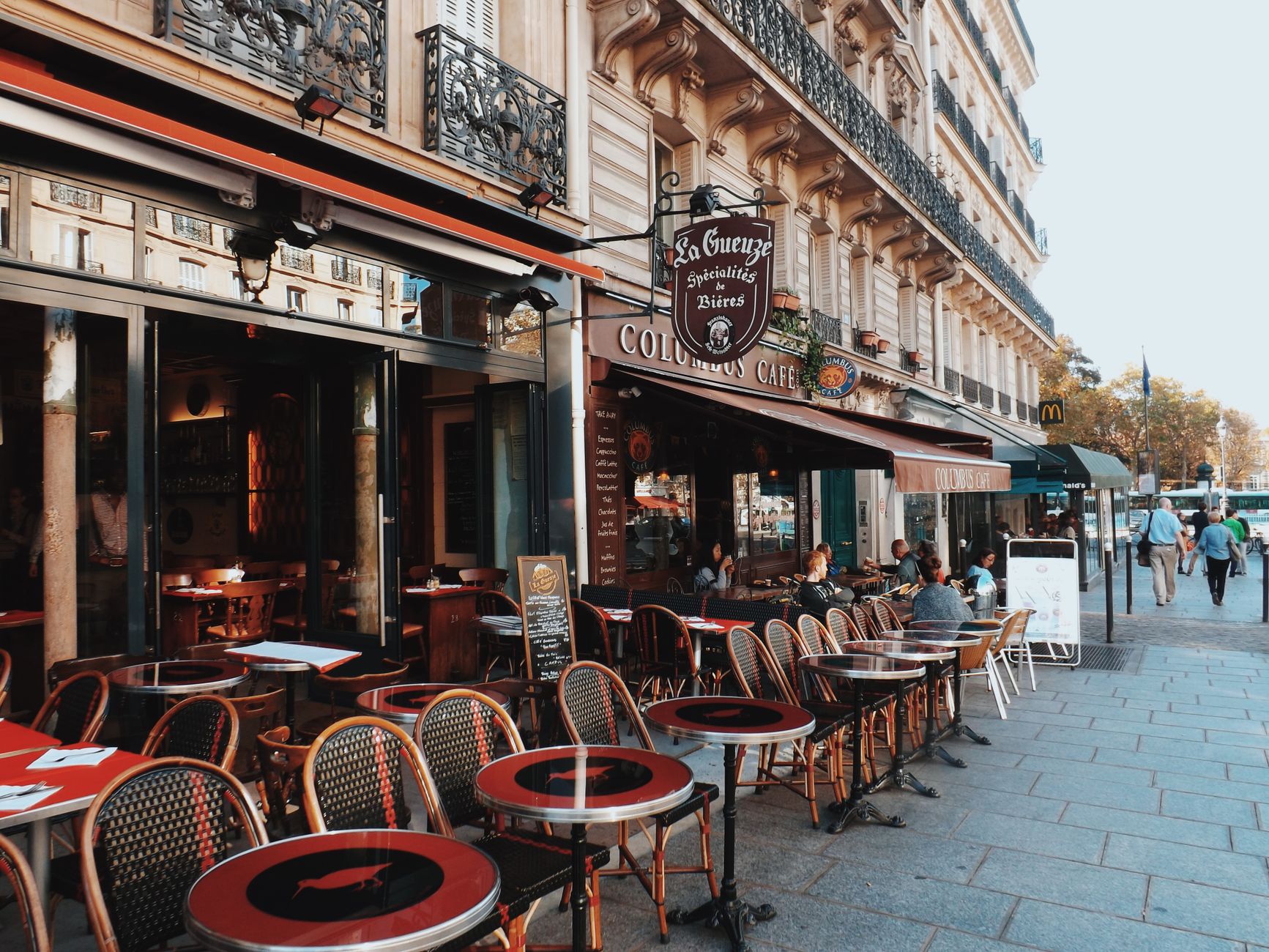 Terraza de café parisino con mesas en la calle y vista a la arquitectura de París