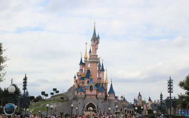 Castillo de Disneyland iluminado con fuegos artificiales por la noche