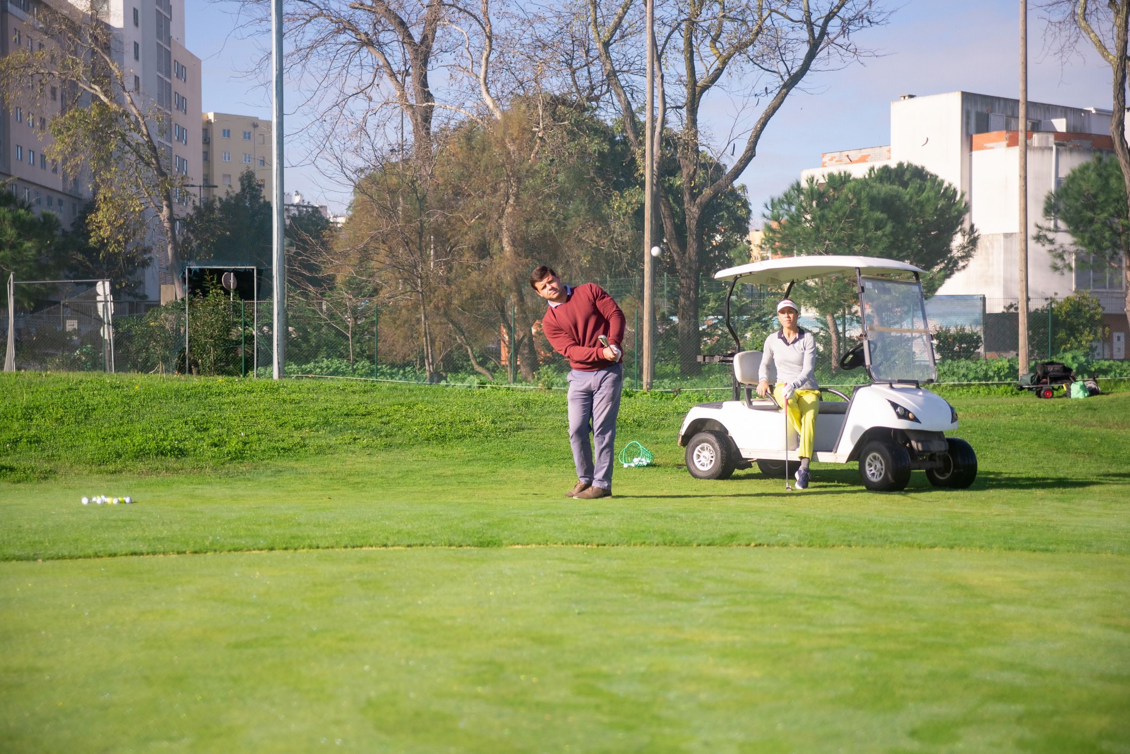 Dos personas jugando al golf en un día soleado con buggy