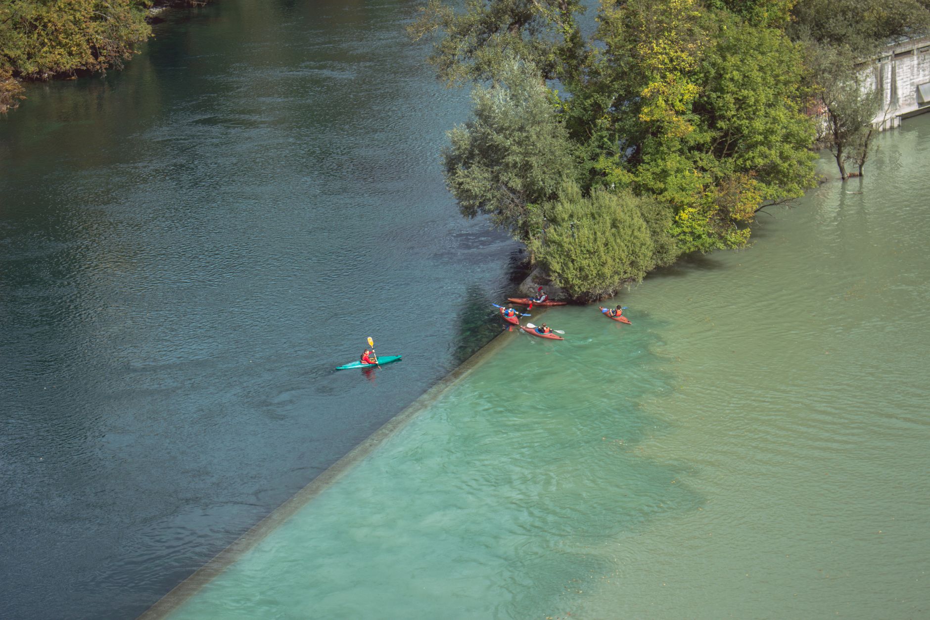 Descenso en canoa por el río Sella: guía práctica 2026 1 Kayakistas en grupo descendiendo por un río entre vegetación frondosa
