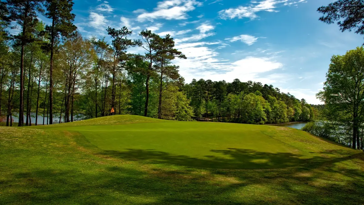 Campo de golf con lago y árboles bajo un cielo despejado