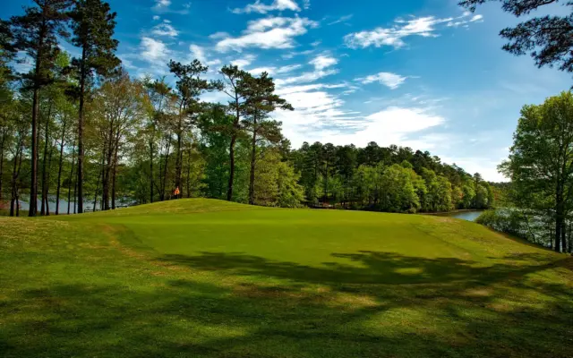 Campo de golf con lago y árboles bajo un cielo despejado