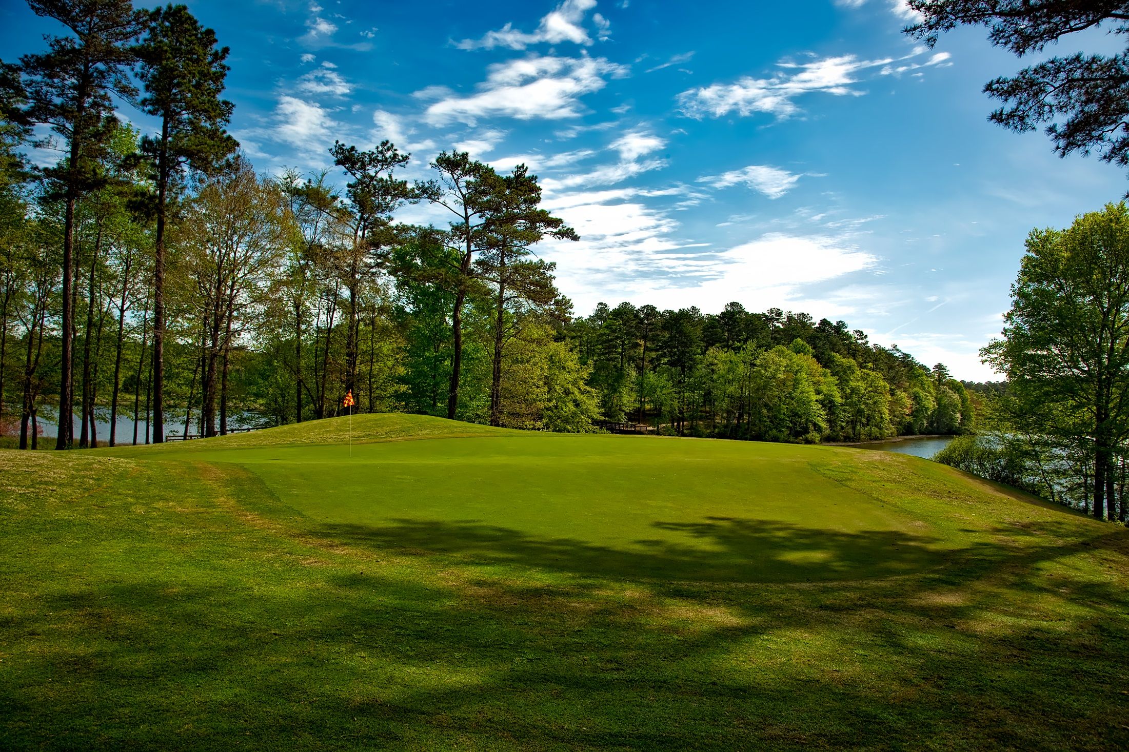 Los campos de golf más extremos del mundo: hielo, géiseres y fauna salvaje 1 Campo de golf con lago y árboles bajo un cielo despejado