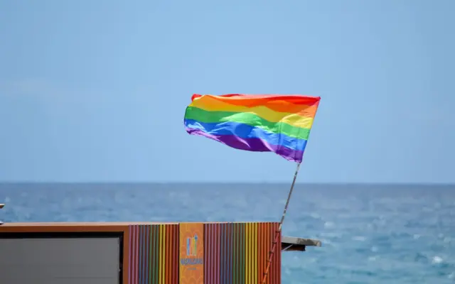 Bandera arcoiris ondeando en la playa de Maspalomas, destino LGBT-friendly de España