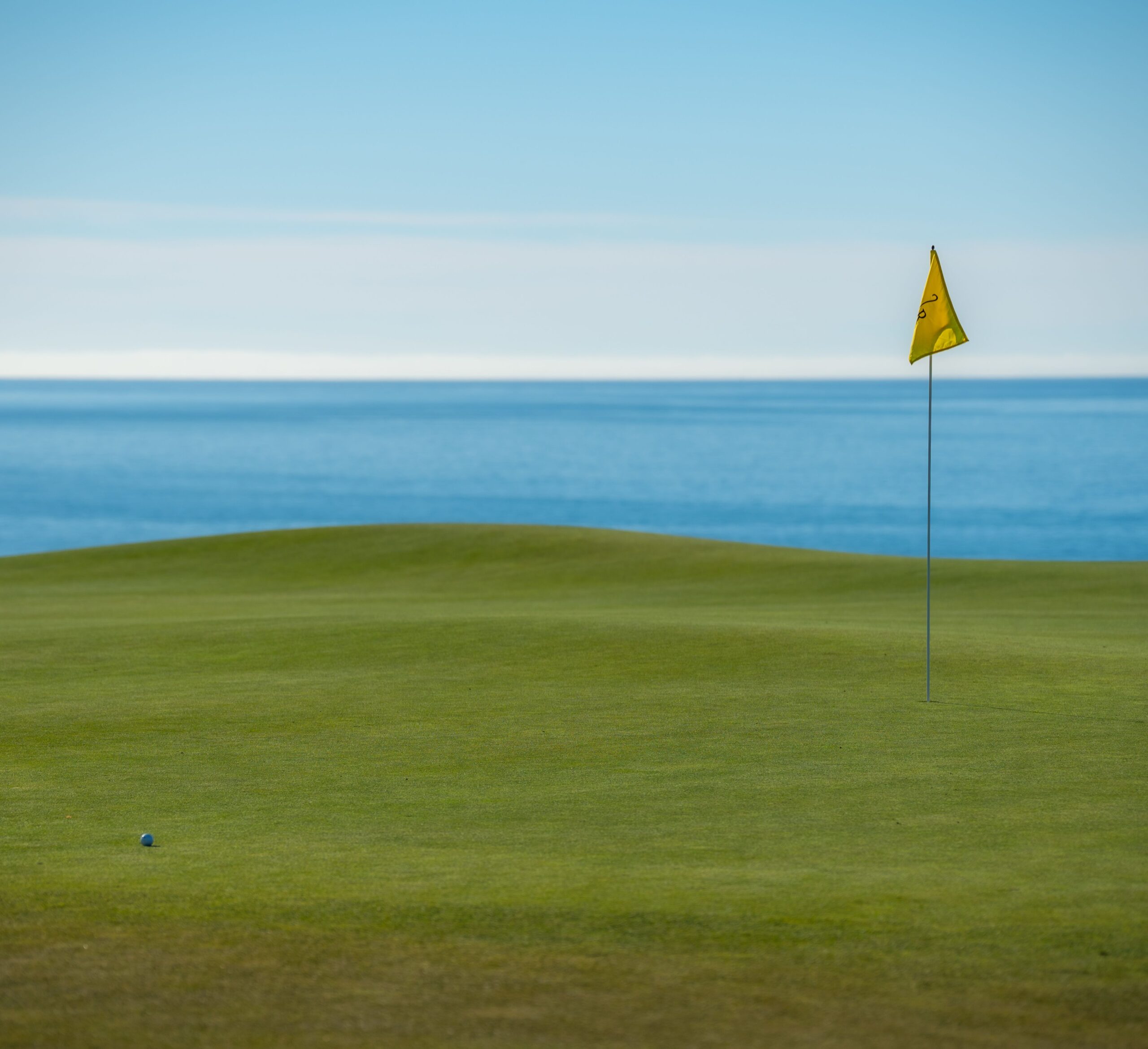 Campo de golf junto al mar con bandera y green de putt