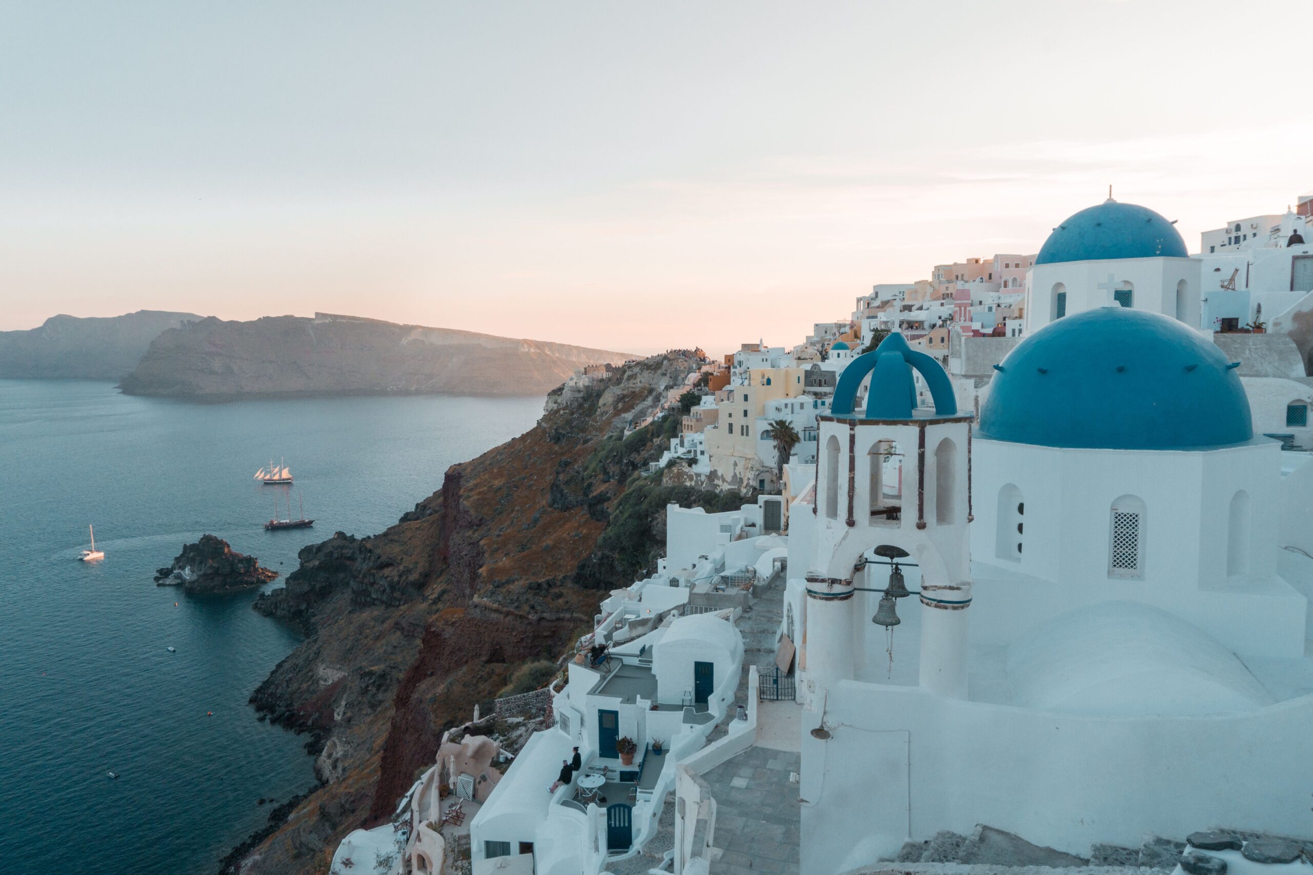 Santorini: guía práctica para la isla de los atardeceres 1 Cúpulas azules de Santorini al atardecer sobre el mar Egeo