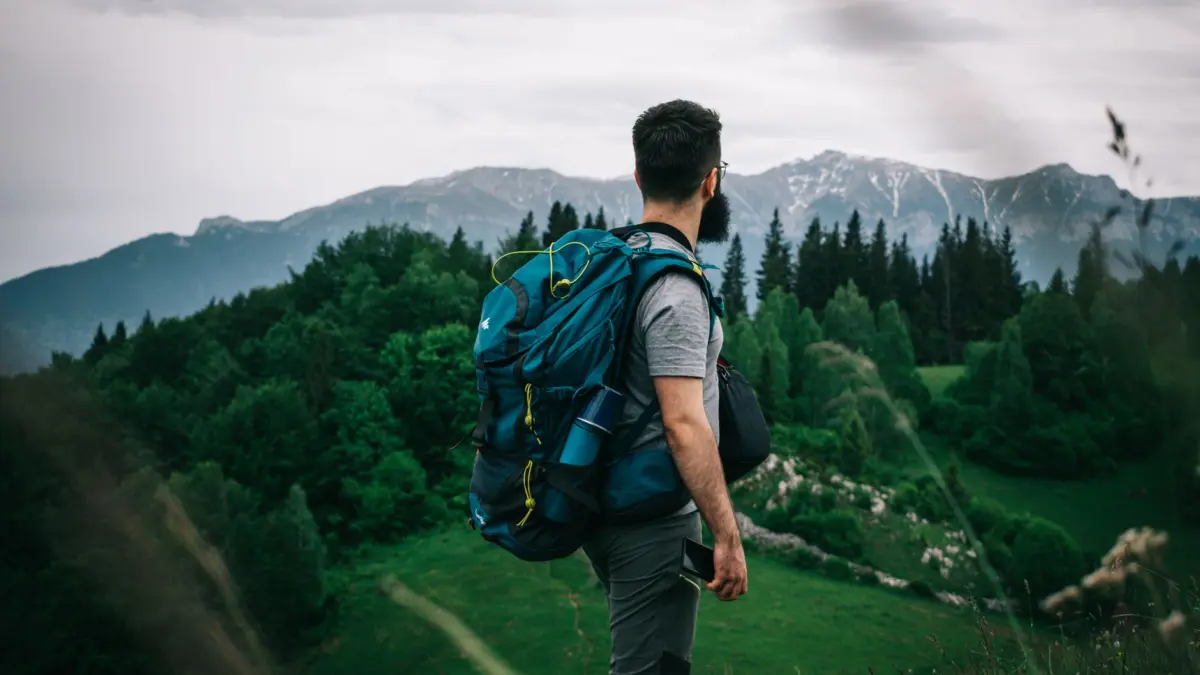 Viajero solo con mochila caminando por la montaña