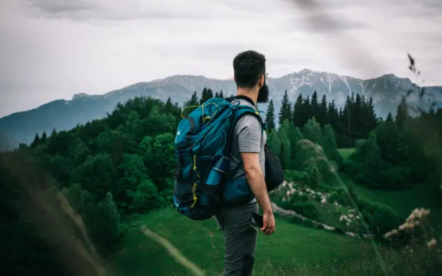 Viajero solo con mochila caminando por la montaña