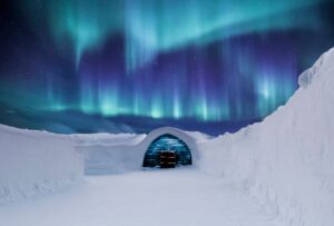 Aurora boreal sobre un iglu transparente cubierto de nieve en el ártico finlandés