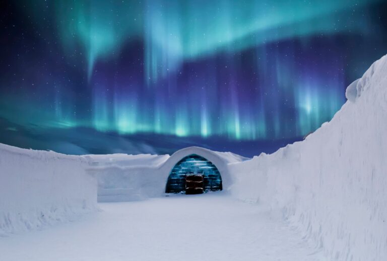 Aurora boreal sobre un iglu transparente cubierto de nieve en el ártico finlandés