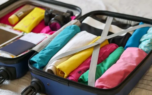 Accesorios de viaje ordenados sobre una maleta abierta
