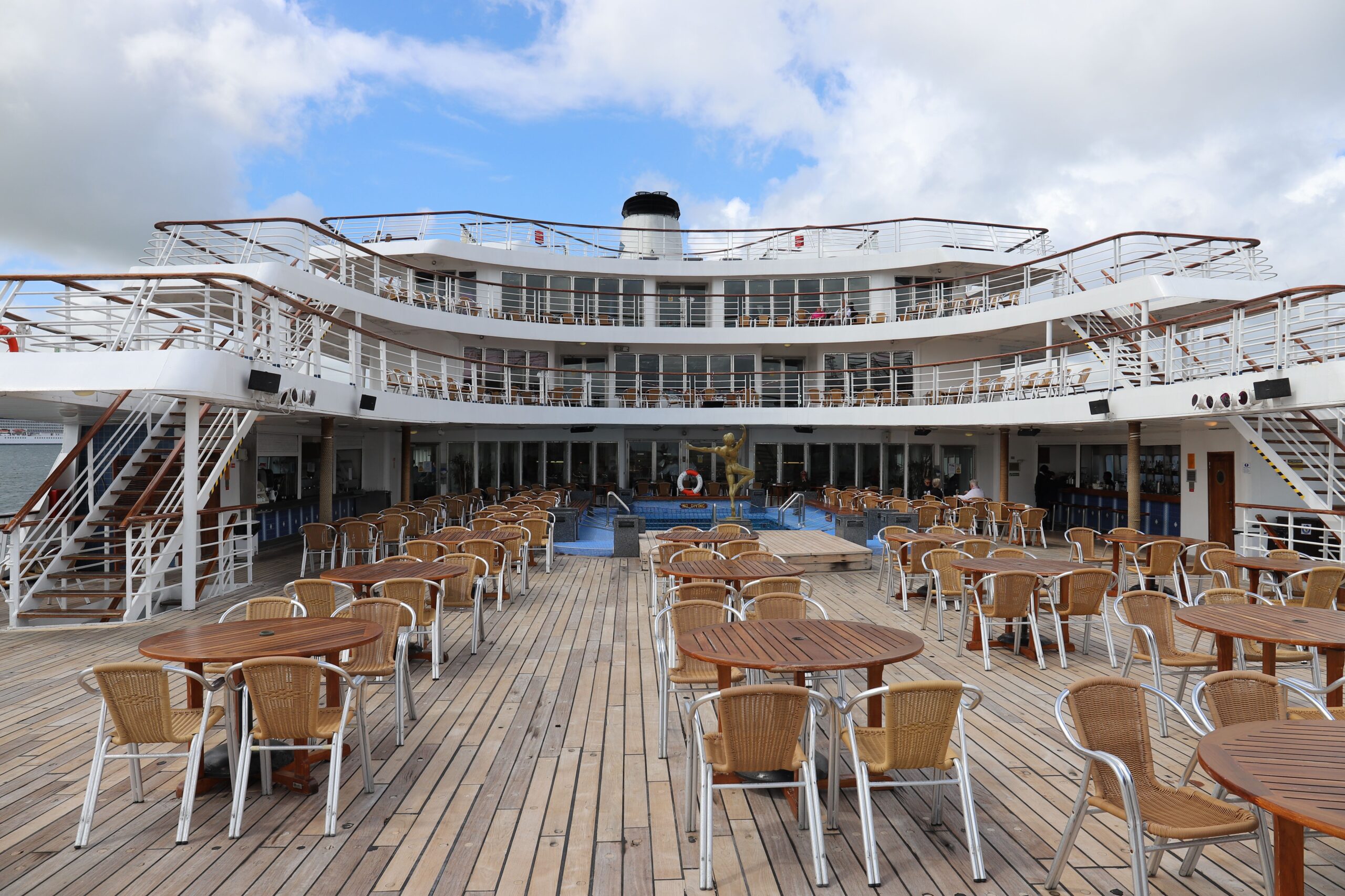 Cubierta vacía de un crucero con mesas y sillas junto al mar