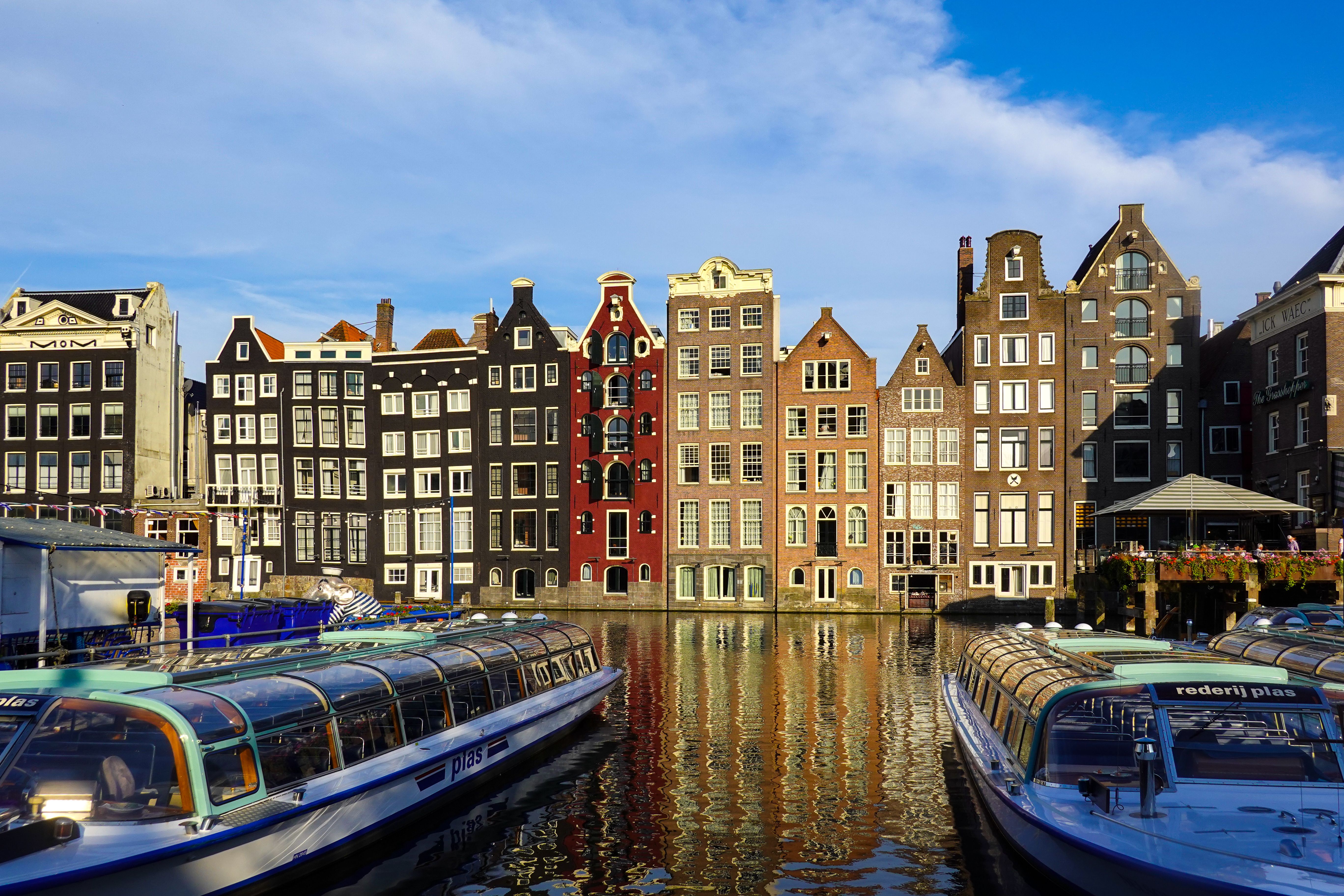 Edificios históricos de colores junto a los canales de Amsterdam con barcos