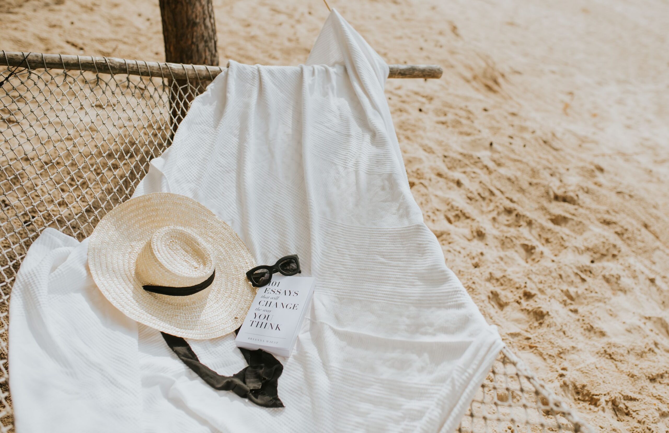 Hamaca en la playa con un libro, sombrero y gafas de sol