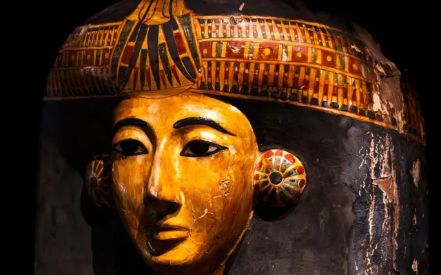 Máscara de sarcófago egipcio con colores vibrantes en un museo