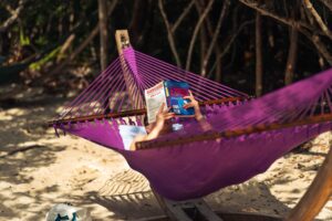 Persona leyendo en una hamaca junto a la playa, sin dispositivos electrónicos