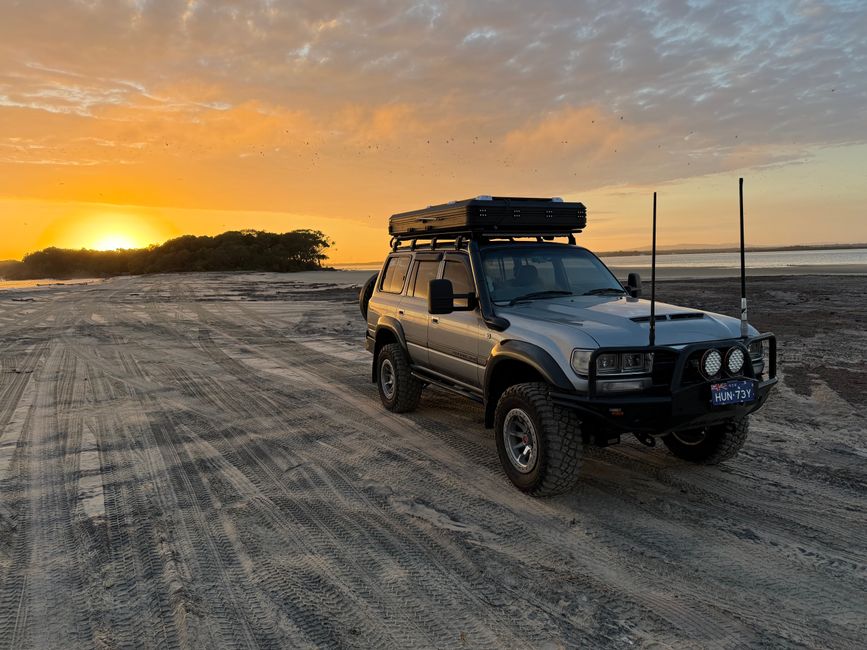 Vehiculo 4x4 circulando por la playa de K'gari durante un atardecer